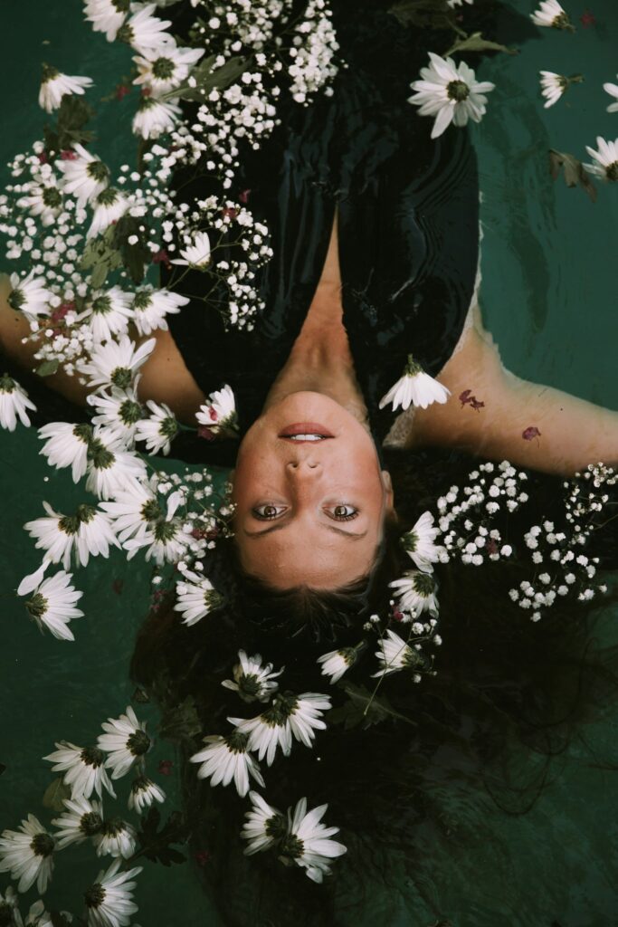 woman on the water with a green dress, surrounded by white flowers